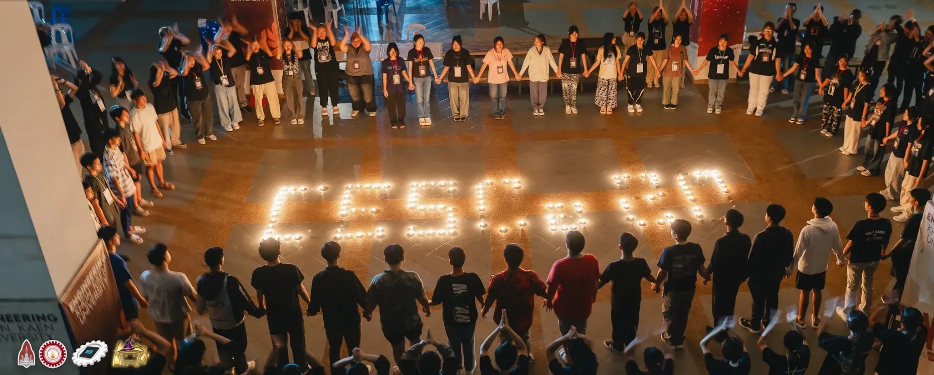 Campers and staff holding hands in a circle around candles that spell CESCa #20, seen from above