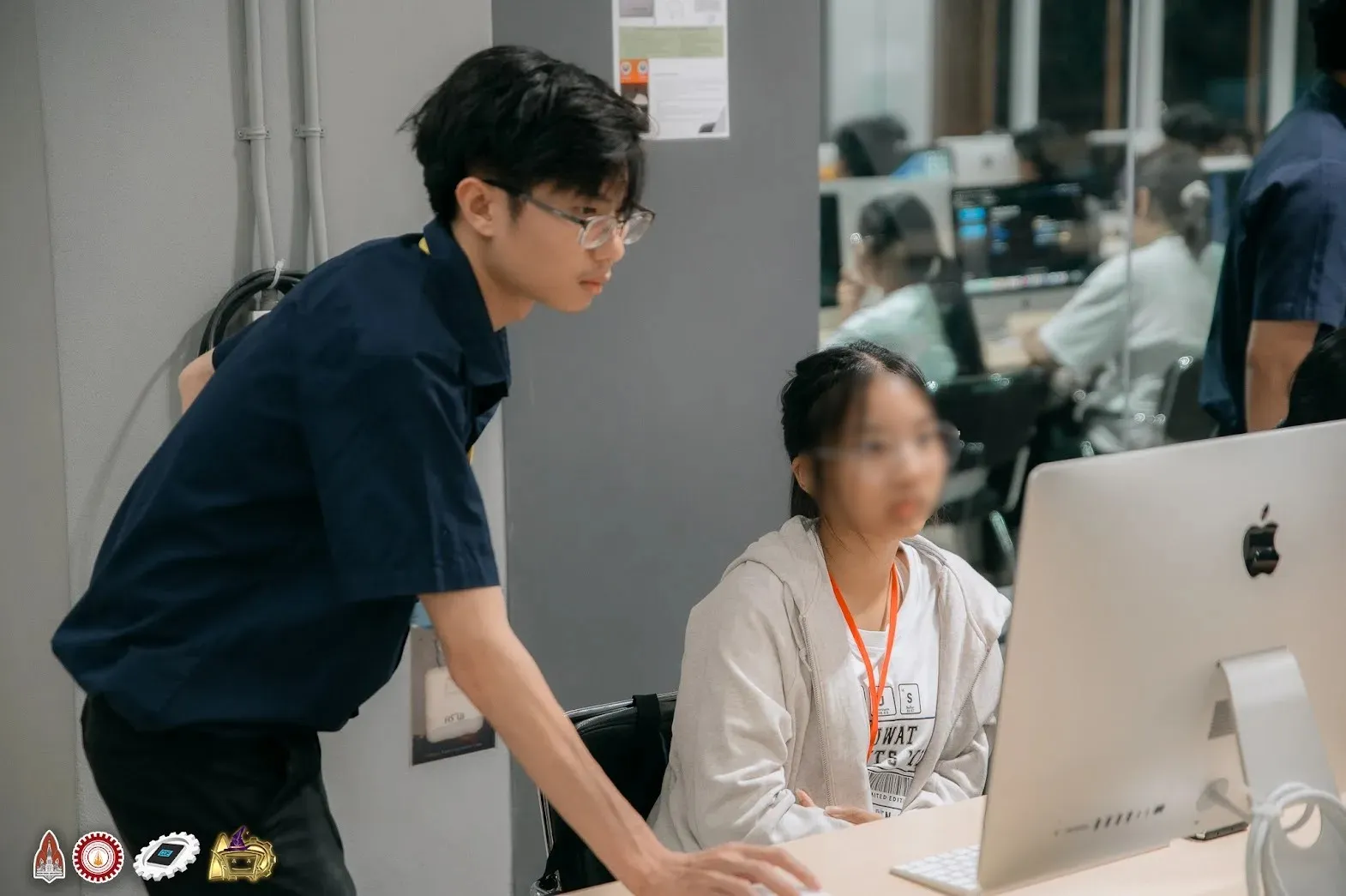 A staff member leaning in to look at a camper’s screen in the computer lab