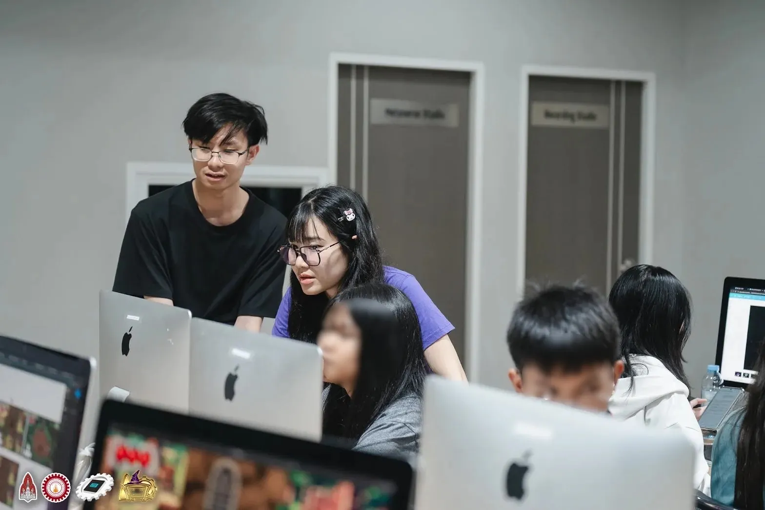 Staff and campers looking at a game project on an iMac in the lab