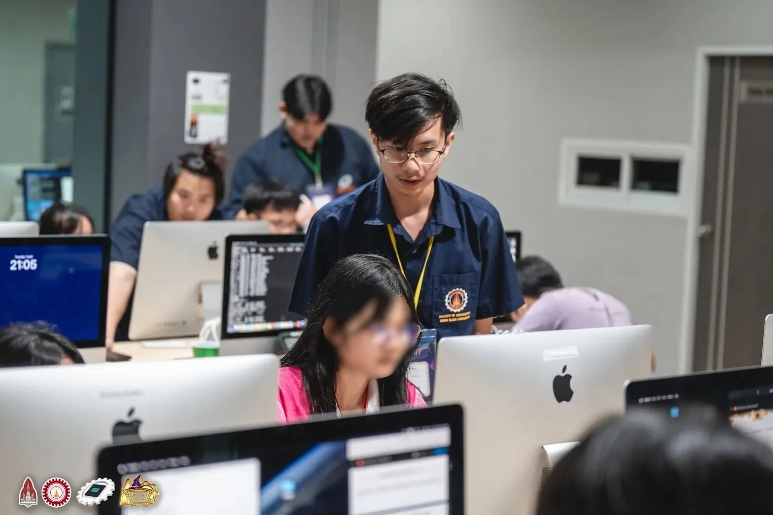 A staff member standing behind a camper at a computer during an evening session