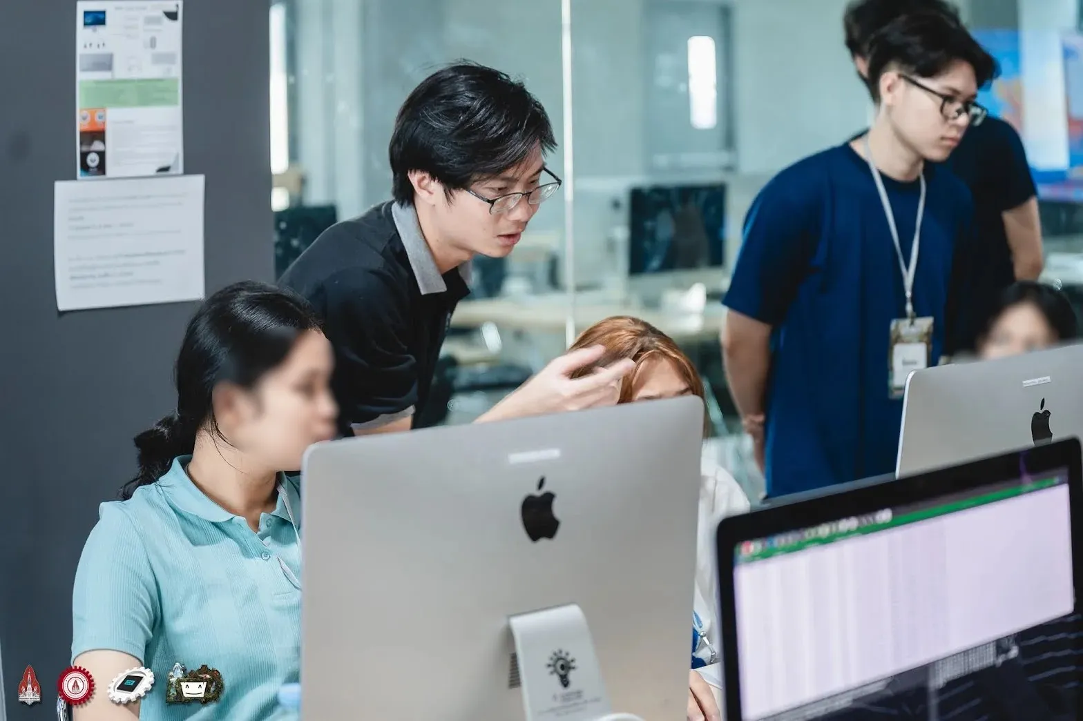 A staff member explaining something at a camper’s computer in the lab