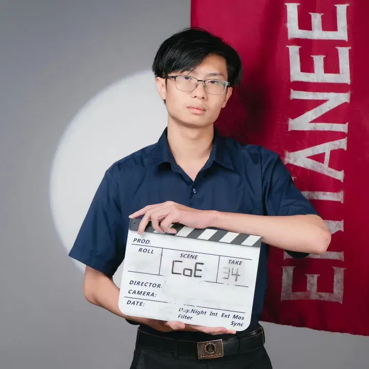 Web in a navy shirt, holding a clapperboard that says CoE 34